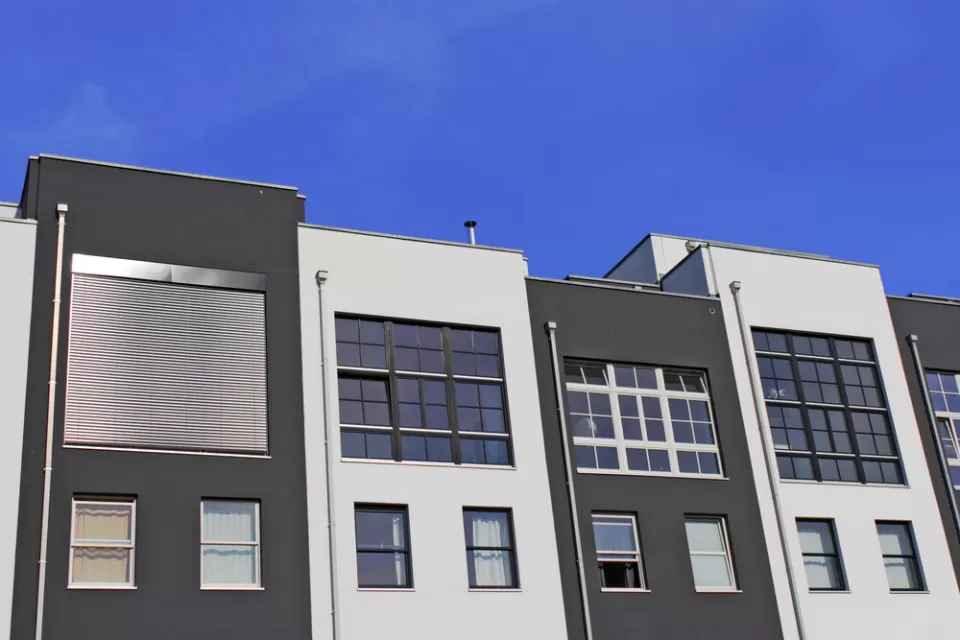 The top floors of a row of pre-fab apartments or condos are shown against a blue sky.